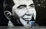 Un cycliste passe devant une peinture murale représentant la légende du tango Carlos Gardel, dans les rues de Buenos Aires, le 24 août 2020