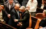 Le ministre israélien des Affaires étrangères Yair Lapid (à droite) et le Premier ministre sortant Naftali Bennett échangent leurs sièges à la Knesset (Parlement), à la suite de la dissolution de la chambre le 30 juin 2022