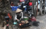 Une vendeuse de rue prépare un "bun cha", une soupe à base de nouilles et de porc grillé, en janvier 2018 à Hanoï, au Vietnam