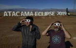 Des touristes essaient des lunettes spéciales pour l'éclipse totale de soleil, le 1er juillet 2019 au campement astronomqiue de Vallenar, dans le désert d'Atacama, au Chili