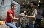 Chaabane Hammouda, qui a lancé un service de livraison de boissons chaudes, donne des instructions à un livreur à vélo devant son stand près du marché de Rafah, dans la bande de Gaza, le 13 juillet 2020