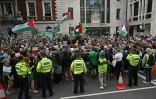 Des policiers encadrent une manifestation de soutien au trio nord-irlandais Kneecap, et à son chanteur Liam O'Hanna alias Mo Chara, où des drapeaux palestiniens sont agités, à Londres le 20 août 2025