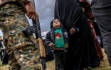 Un enfant regarde un combattant des Forces démocratiques syriennes après avoir quitté le dernier réduit du groupe Etat islamique à Baghouz, dans l'est syrien, le 27 février 2019