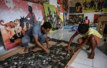 L'artiste ivorien Mounou Désiré Koffi (G) et l'un de ses ouvriers dans son atelier à Abidjan, le 28 avril 2022