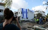 Une femme prend une photo d'un drapeau israélien déployé sur le mur d'un bâtiment endommagé à Kiryat Bialik dans le district de Haïfa en Israël, à la suite d'une attaque du Hezbollah libanais, le 22 septembre 2024
