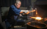 Le forgeron Akihira Kawasaki martèler de l'acier pour forger une lame de katana dans son atelier à Misato, le 9 janvier 2026 au Japon