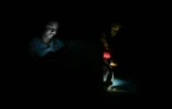 Des femmes s'éclairent avec leur téléphone portable à La Havane, le 20 octobre 2024, en pleine coupure d'électricité