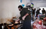 Le chef cuisinier syrien Talal Rankoussi (c) prépare un repas pour les réfugiés du camp de Ritsona, au nord d'Athènes, le 21 décembre 2016 en Grèce