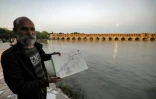 Un homme pose avec un dessin devant le pont historique Si-o-Se Pol, le long de la rivière Zayandeh-roud, à Ispahan dans le centre de l'Iran, le 15 mai 2022