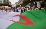 Des Algériens arborent un géant drapeau national lors d'une manifestation contre le président Abdelaziz Bouteflika, le 19 mars 2019 à Alger