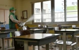 Un employé désinfecte une salle de classe dans un lycée de Séoul le 19 mai 2020