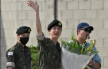 Jin (c), membre du boys band BTS, salue après avoir été libéré de son service militaire à côté des autres membres RM (d) et Jimin (g) à l'extérieur du camp d'entraînement de Yeoncheon, en Corée du Sud, le 12 juin 2024