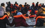 Des migrants montent à bord d'un bateau de passeurs pour traverser la Manche, au large de la plage de Gravelines, le 16 juin 2025 dans le Nord