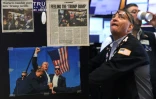 Des coupures de presse et une image du président américain Donald Trump affichées sur un bureau alors que les traders travaillent sur le parquet de la Bourse de New York (NYSE) à la cloche d'ouverture, le 9 avril 2025 à New York