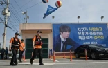 Des pompiers passent devant une bannière montrant une photo de Jin, membre du groupe de K-pop BTS, devant le camp d'entraînement de Yeoncheon, le 12 juin 2024