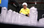 L'employée Michaela Trebes inspecte les flacons sur une ligne de production de l'entreprise Heinz-Glas, le 3 août 2022 à Kleintettau, en Allemagne
