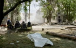 Des secouristes sont assis devant un corps sans vie avec un bâtiment effondré en arrière-plan après une frappe russe à Kramatorsk le 22 juin 2025