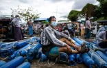 Un homme assis fait la queue pour remplir des bouteilles d'oxygène à Mandalay le 13 juillet 2021