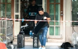 Un enquêteur emporte un ordinateur hors de la maison où un adolescent a tué ses grands-parents avant de perpétrer une fusillade dans une école au nord de Bangkok, la capitale de la Thaïlande (7 août 2026)