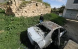 Un Palestinien à proximité d'un véhicule calciné après une attaque attribuée à des colons israéliens à Jalud, près de Naplouse, en Cisjordanie occupée, le 22 mars 2026
