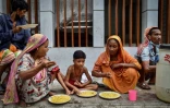 Des personnes apauvries par la crise du coronavirus mangent un repas offert par l'association Mehmankhana, le 26 juillet 2021 à Dacca