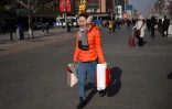 Une femme marche dans une rue commerciale à Pékin, le 18 janvier 2018