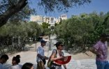 Des touristes restent à l'ombre, devant les portes closes du site archéologique de l'Acropole à Athènes, fermé pour cause de chaleur excessive, le 2 août 2021