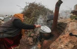 Une femme cuisine en plein air dans un camps de déplacés, le 17 décembre 2021 dans le nord-ouest de la Syrie