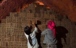 Des femmes entreposent des briques dans une manufacture de briques, près de Phnom Penh, le 11 décembre 2018