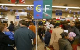 Des clients s'apprêtent à régler leurs achats aux caisses en euros (G) ou en francs, le 5 janvier 2002 dans un supermarché à La Défense, près de Paris