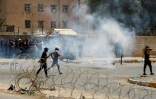 Des partisants du leader Sadr tentent d'échapper aux tirs de gaz lacrymogène lors d'une manifestation à Bagdad, le 30 juillet 2022