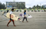 Les surfeurs Mohammad Mannan et Fatima Akhter sur la plage de Cox's Bazar, dans le sud-est du Bangladesh, le 22 juin 2026