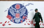 Un Gardien de la Révolution iranien passe devant une fresque murale sur l'enceinte de l'ancienne ambassade américaine à Téhéran, le 2 novembre 2019