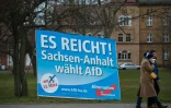 Un couple marche près d'une affiche de campagne du parti Alternative pour l'Allemagne (AfD), portant le slogan "ça suffit !", le 11 mars 2016 à Magdebourg, en Allemagne