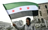 Un homme agite le drapeau de l'indépendance syrienne, dans les ruines d'Alep, dans le nord de la Syrie, le 11 décembre 2024