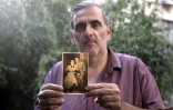 Gili Grunbaum, 60 ans, d'origine tunisienne, pose avec un portrait de ses parents adoptifs le 6 juillet 2016 à Ramat Gan près de Tel Aviv