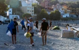 Des migrants restés à Ceuta marchent sur une plage de l'enclave espagnole au Maroc après avoir reçu de la nourriture de la Croix-Rouge, le 22 août 2026