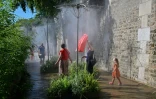 Des personnes se rafraîchissent sous un brumisateur sur les quais de la Seine, pendant un épisode de canicule, le 21 août 2023 à Paris
