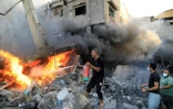 Un Palestiniens tente d'éteindre un incendie après une frappe israélienne qui a détruit une habitation à Khan Younès dans le sud de la bande de Gaza, le 14 octobre 2023