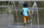 Un enfant se rafraîchit dans une fontaine pendant une vague de chaleur, le 1 juin 2022 à Montpellier