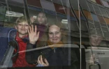 Des personnes font un signe de la main à travers la vitre d'un véhicule après avoir quitté l'ambassade de Russie à Londres, le 20 mars 2018