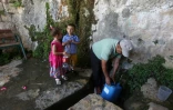 Abdel Fattah Salim, remplit son bidon d'eau de pluie le 23 juin 2016 à Salfit (nord de la Cisjordanie)