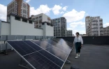 Anastasia Kyslinska, directrice de l'école Spilno, inspectent les panneaux solaires sur le toit de son établissement pendant une panne d'électricité partielle à Kiev, le 18 juin 2024 en Ukraine