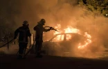 Un pompier lutte contre les flammes d'une voiture incendiée dans le quartier Malakoff de Nantes, le 4 juillet 2018