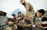 Un soldat des forces armées irakiennes tente de contenir des familles de déplacés qui attendent de la nourriture, le 24 octobre 2016 à Al-Qayyarah