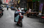 Une femme à moto, le visage couvert d'un masque de protection, dans une rue de Huanggang, dans la province chinoise du Hubei, le 26 mars 2020