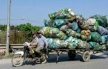 Deux hommes tractent à moto des déchets en plastique destinés à être recyclés aux alentours de Hanoï, au Vietnam, le 25 novembre 2025