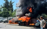 Un homme prend des photos de véhicules en feu après une frappe israélienne, le 10 juin 2026 à Saïda au Liban