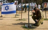 Un soldat israélien se recueille devant des photos de personnes capturées ou tuées par des militants du Hamas lors du festival de musique Supernova le 7 octobre, sur le site où l'attaque meurtrière a eu lieu, près du kibboutz Reim, dans le sud d'Israël, le 5 janvier 2024