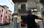 Un homme se tient devant une maison de l'époque fasciste, avec des écrits et des dessins représentant le défunt leader fasciste italien Benito Mussolini, dans la rue du vieux centre de la ville de Cinquefrondi, dans la région de Calabre, au sud de l'Italie, le 6 juillet 2020. 